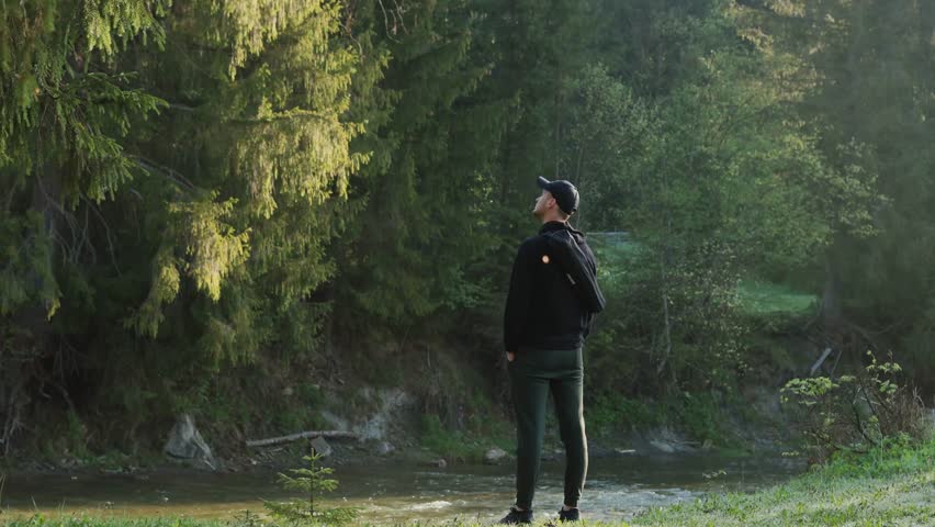 A man standing in the woods, admiring the trees