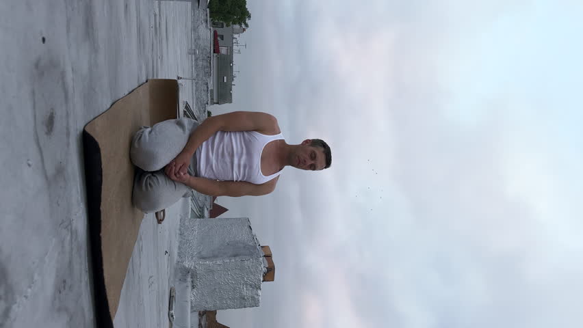 Timelapse view of an athletic man doing Sudarshan Kriya, the powerful cyclic breathing technique, and Sahaj Samadhi Meditation, a mantra-based meditation on the building roof | Shutterstock HD Video #1107544421