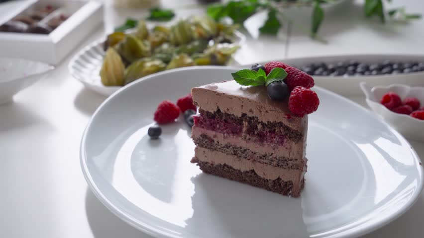 A beautiful piece of chocolate cake decorated with berries on a white platter.