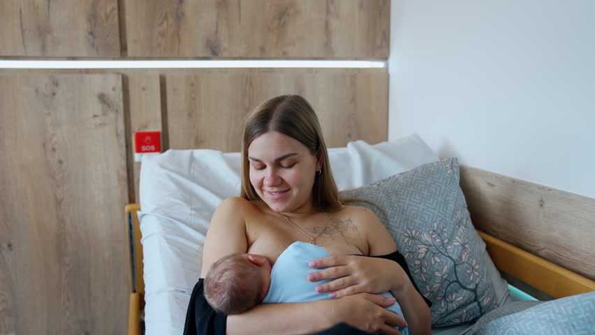 Lady with newborn baby in nursery ward. Modern pregnant hospital room.