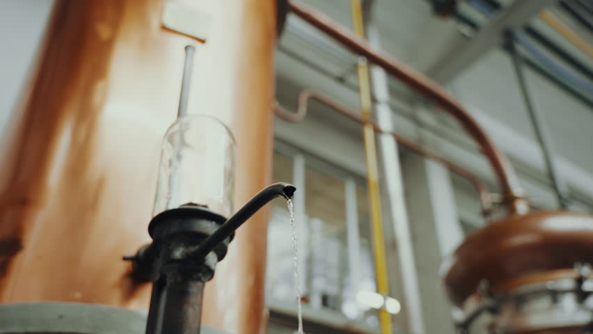 Close up shot of distilled alcohol coming out of a copper tank, industrial process in a gin distillery production Royalty-Free Stock Footage #1107546399