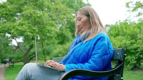 asian woman in blue jacket using laptop in public park using internet everywhere Lifestyle concept	