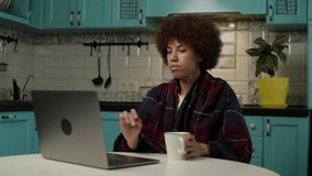 Black Woman Wrapped in Plaid Watching Movie on Laptop. Female enjoys her favourite series sitting at cold home.