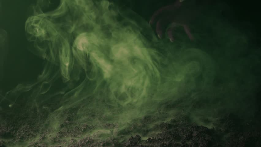 A terrible hand with claws emerges from the fumes of smoke over the graveyard ground.