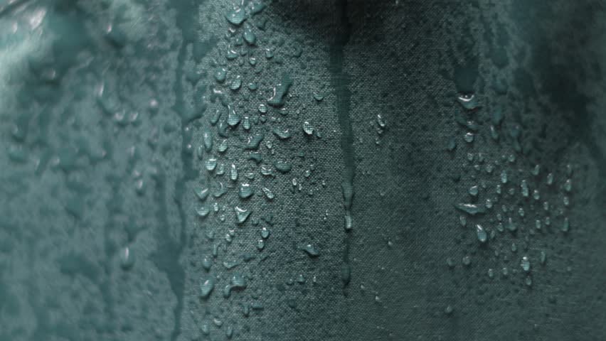 Falling water drops on waterproof membrane jacket. Slow motion 4K close-up of fabric does not let raindrops through. Royalty-Free Stock Footage #1107549637
