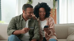 Multiracial African American Arabian family hold mobile phone and bank credit card online shopping couple clients woman and man booking delivery at home paying money budget happy look at camera smile - Powered by Shutterstock - Get 15% off with code: PIKWIZARD15