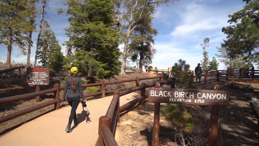 Black Birch Canyon Viewpoint Sign in Bryce Canyon National Park, Utah USA and Woman Walking on Path
