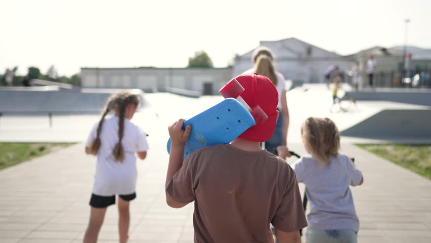 Happy cheerful children amusement park.Children in park engaged in active sports, riding skateboard, rollerblading, scooter. Children spent fun day park playing sports. Happy active childhood in park.
