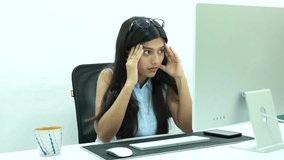 Shot of an Indian Girl having headache while working on a Computer in office
