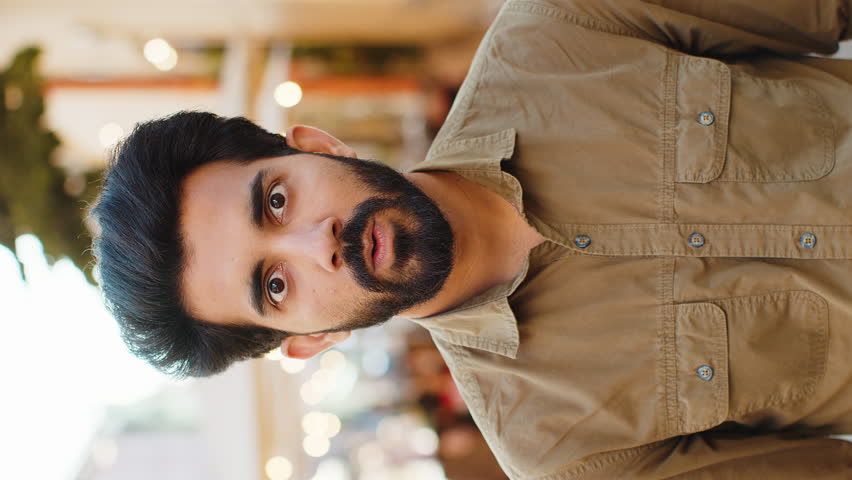Oh my God, Wow. Indian man looking surprised at camera with big open eyes, shocked by sudden victory, game winning, lottery goal achievement, good news outdoors. Guy in city sunshine street. Vertical