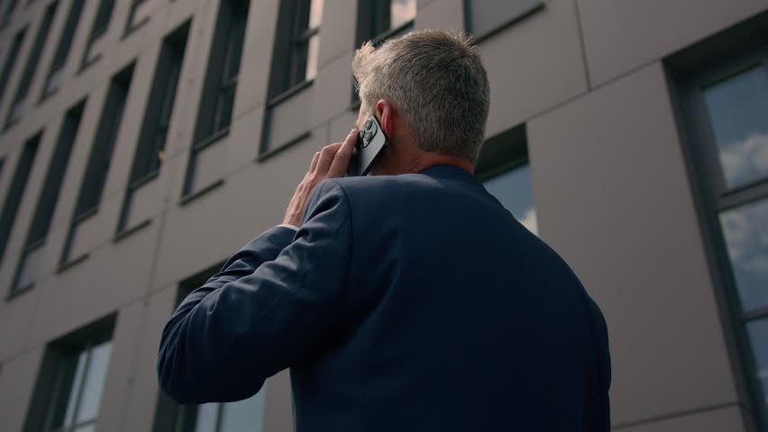 Back view unrecognizable employer entrepreneur outdoors mature business man looking on office company building real estate developer realtor negotiate mobile phone talking call businessman in city Royalty-Free Stock Footage #1107570571