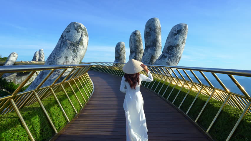 4k slow motion,Asian woman wearing white.Vietnamese culture with traditional conical hat withon the Golden Bridge, Da Nang City, Vietnam. Royalty-Free Stock Footage #1107573915