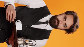 Vertical video Elegant waiter carrying platter with drinks and cutlery to serve customers at five star restaurant, stylish catering employee with towel over arm. Professional worker using tray and - Powered by Shutterstock - Get 15% off with code: PIKWIZARD15