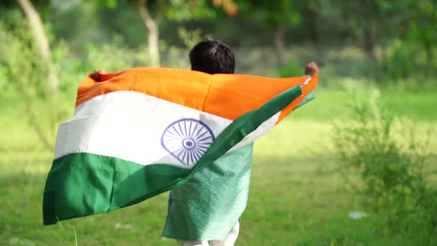 Happy Cute little indian kids holding, waving or running with Tricolour with greenery in the background, celebrating Independence or Republic day