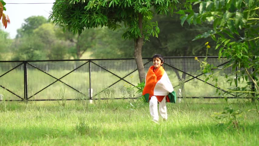Happy Cute little indian kids holding, waving or running with Tricolour with greenery in the background, celebrating Independence or Republic day