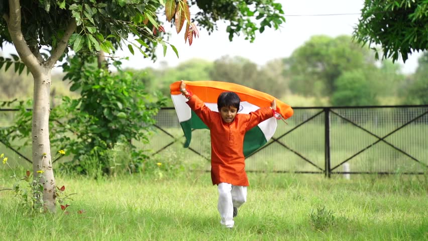 Happy Cute little indian kids holding, waving or running with Tricolour with greenery in the background, celebrating Independence or Republic day