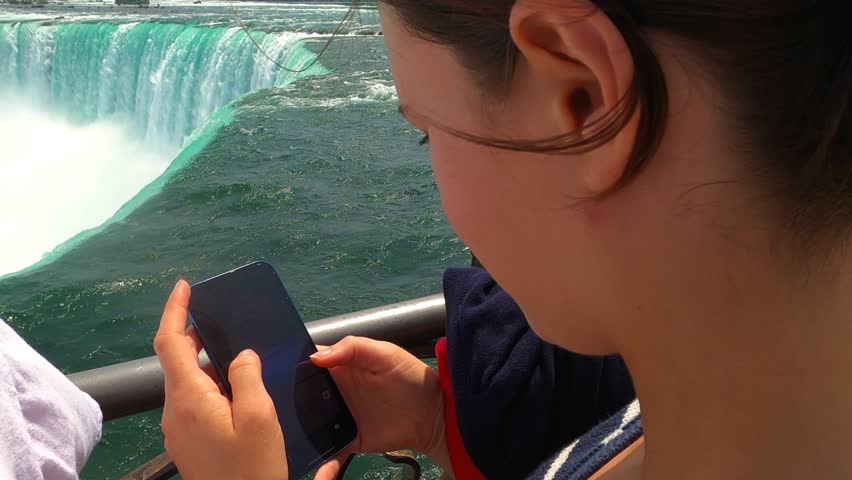 A youthful woman captures fleeting moments with her cell phone camera.