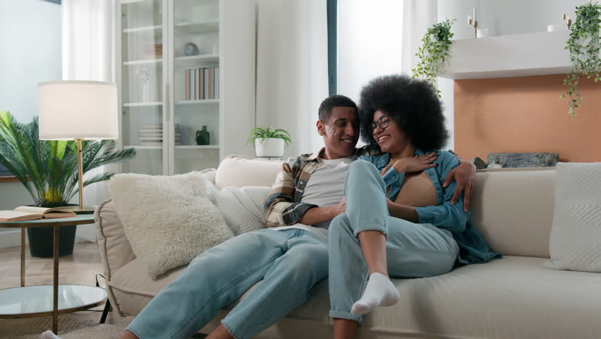 Smiling laughing carefree African American happy family couple married woman girl man guy boyfriend and girlfriend domestic dating bonding conversation laugh funny love affection talking at home couch Royalty-Free Stock Footage #1107606179