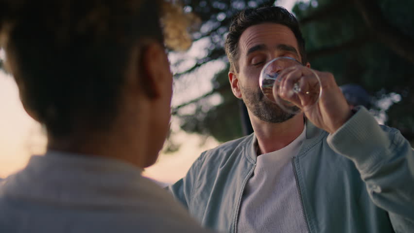 Couple friends enjoy meeting in sunset weekend closeup. Handsome latino man listening unknown woman talk sipping alcohol beverage. Bearded happy guy speaking with curly female colleague after work Royalty-Free Stock Footage #1107610541