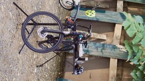 Vertical video Two bicycles in backyard waiting for repair and maintenance with professional equipment as annual summer activity. Broken bike positioned on repair-stand for examining and fixing