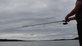 Man fishing a cloudy day. Mälaren lake, Sweden, 2023.