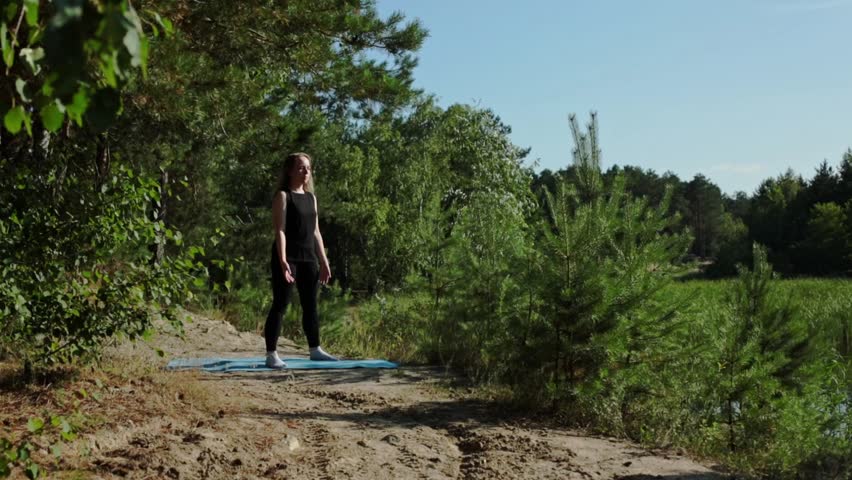 Girl crouches in the park on a rug