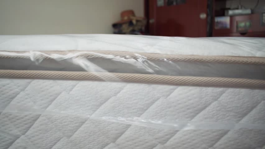 Man uncovering mattress with scissors in a bedroom Royalty-Free Stock Footage #1107618759