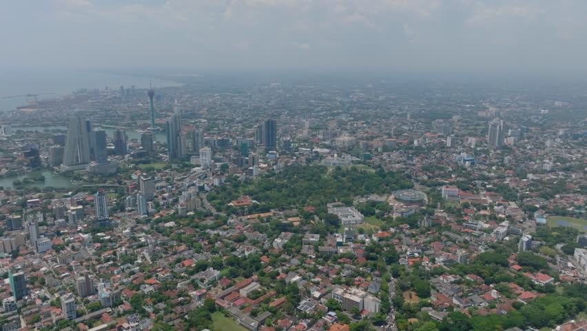 Aerial panoramic footage of metropolis. Forwards fly high above large city in flat landscape. Group of modern high rise buildings and famous Lotus Tower. Colombo, Sri Lanka
