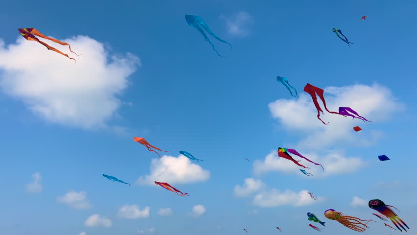 Many different colorful kites are flying in the blue sky with clouds and swaying in the wind during summer outdoor festival. Childhood, freedom and leisure time concept Royalty-Free Stock Footage #1107622545