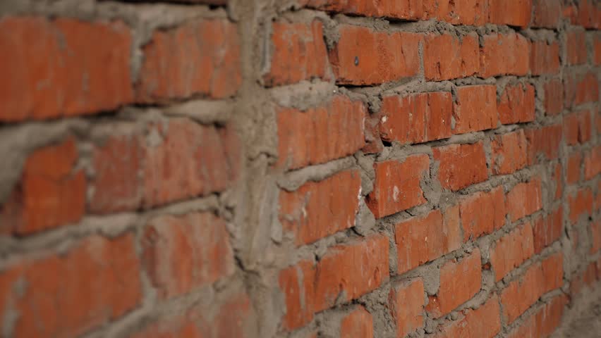 Close-up of an old brick wall in a ruined building. The windows at the abandoned factory were laid with red bricks. A red brick wall on a construction site.