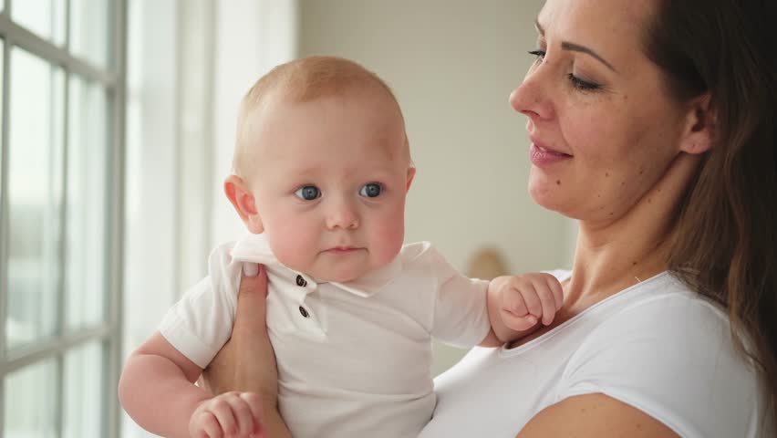 Happy family at home. Mother holding little toddler child daughter. Mom and baby girl relax playing having fun together at home. Mother hugs baby with love care. Mom of breast feeding baby