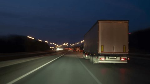 Speedy truck with semi-trailer drives on highway at night along big city timelapse. Arkivvideo