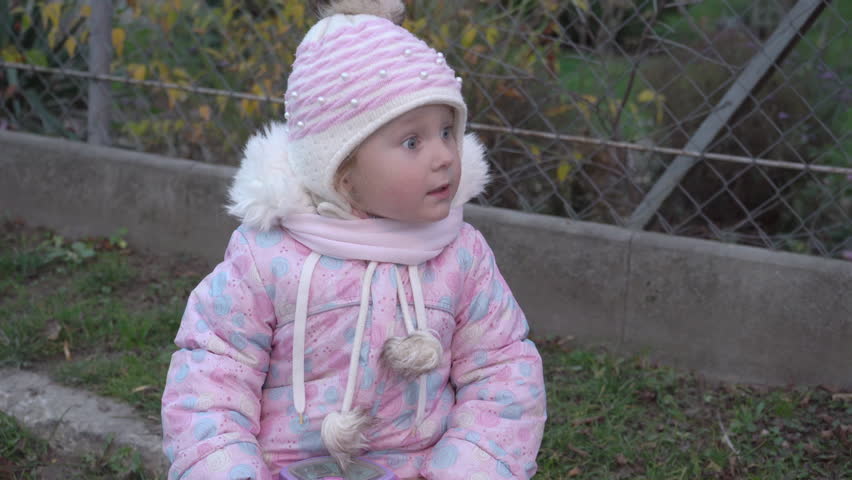 little girl shows with emotions in autumn,the child saw something and points with his hand, the girl is dressed in autumn