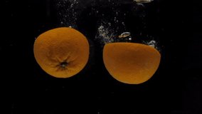 Slow motion orange halves falling into transparent water on black background. Fresh citrus splashing in aquarium. Fruits, healthy food, diet, air bubbles - Powered by Shutterstock - Get 15% off with code: PIKWIZARD15