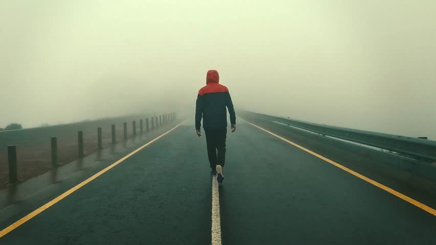 A man walking into the fog on the line of a lonely street with a hood Royalty-Free Stock Footage #1107638619