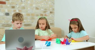 Boy and girls fold origami according to a video lesson, online training