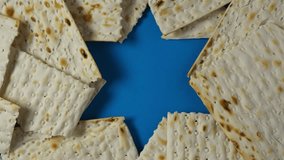 Matzah or Matzo kosher food on blue background with David Star. Jewish traditional Passover bread. Pesach celebration symbol. 4K Video, Rotating.