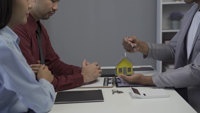 Real estate broker showing house details on her file to young asian couple interested in buying a new home and offering conditions and signing home purchase contract and home insurance concept Royalty-Free Stock Footage #1107644599