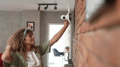 adult caucasian woman adjust prepare home surveillance security camera, videoclip de stoc