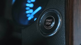 Finger presses the ignition button on the car dashboard and the lights turn off. Hand engages the button, initiating car turns off process.