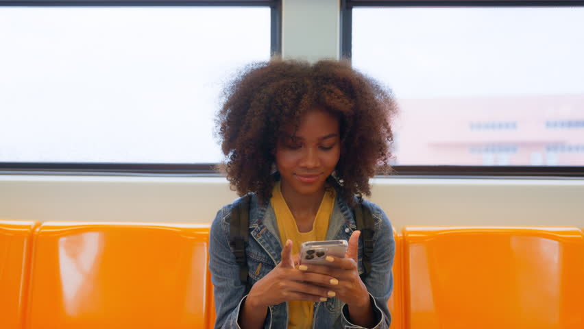 Black young woman, using smart phone and smile in skytrain. Happy african student, young female chatting and typing text message on mobile Royalty-Free Stock Footage #1107657945