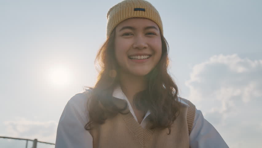 Young Gen Z girl asia people curly brown hair, face, eye smile in blue sky sun light lens flare. Teen urban city life happy joy of future hope enjoy warm time relax sunset. Good mental health teenage. Royalty-Free Stock Footage #1107658517