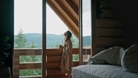 A young woman in a bathrobe stands on the terrace of a country log house and enjoys her morning coffee and fresh mountain air. - Powered by Shutterstock - Get 15% off with code: PIKWIZARD15