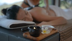 Close up of aroma lamp at the massage table with girl lying on it, back massage with stones and hands, relaxation in health spa resort, body care concept - Powered by Shutterstock - Get 15% off with code: PIKWIZARD15