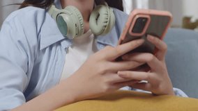 Close Up Of Bored Asian Teen Girl Using Smartphone While Sitting On Sofa In The Living Room At Home
