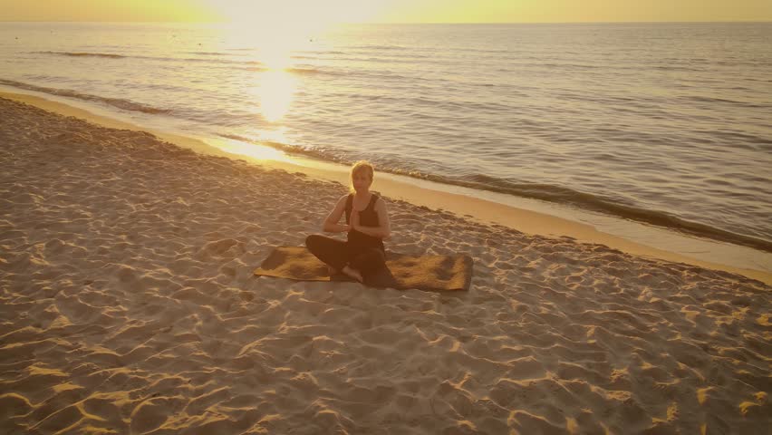 Adult woman sitting in meditation pose on Indian beach lotus position medicine yoga asana balance kundalini energy every day routine practice. Healthy lifestyle, movement concept, meditation and