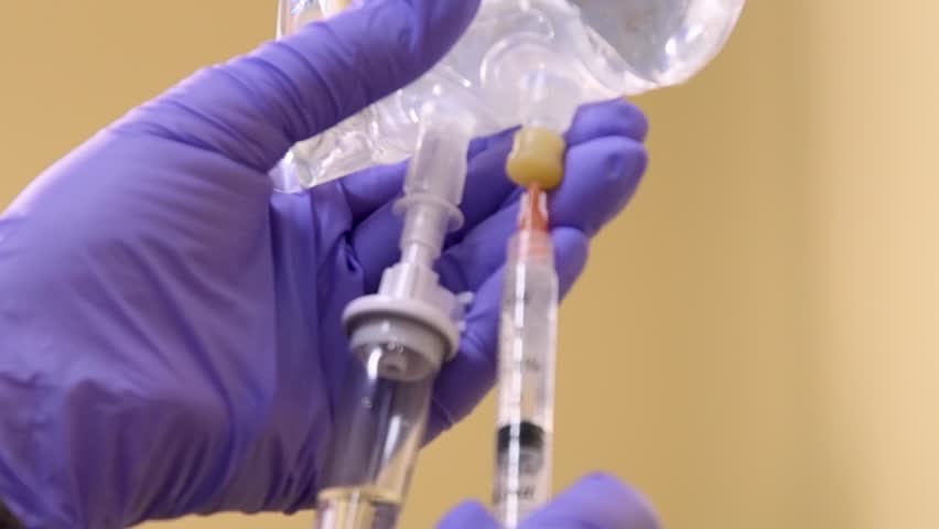 Close-up of nurse using syringe to put medication into patient's IV bag. Royalty-Free Stock Footage #1107678731