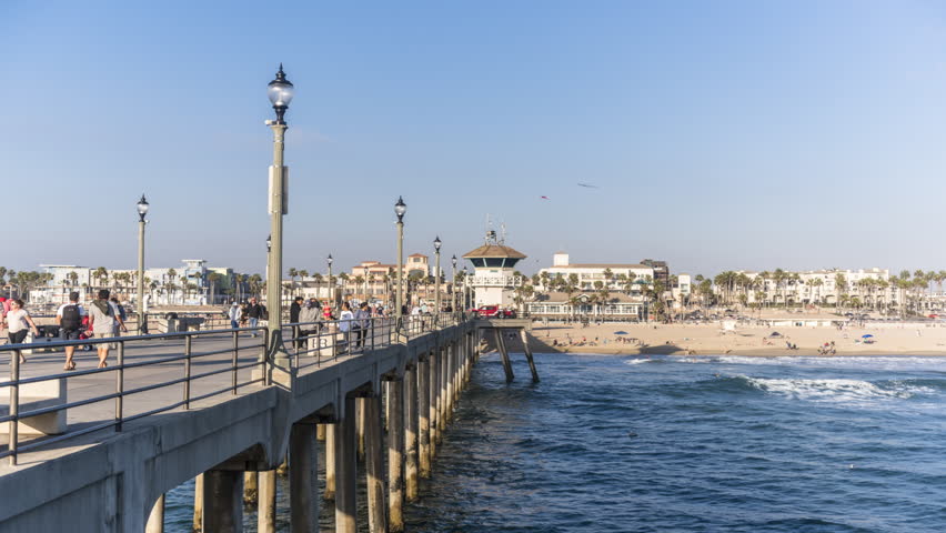 Huntington Beach Pier in California shows the non-stop hustle and bustle of tourist traffic as day becomes night and the local pier and city lights brighten to give a festive effect 
