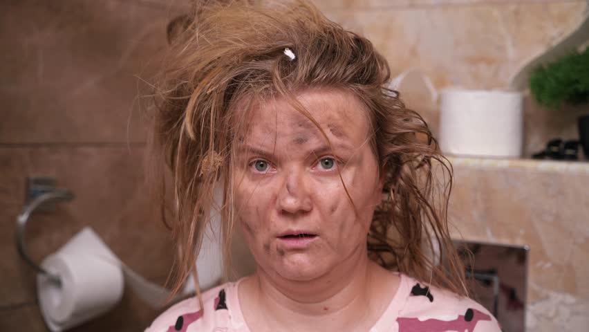 Blonde woman with dirty face and disheveled hair sits in bathroom after explosion. Lady looks around toilet with dazed and shocked expression | Shutterstock HD Video #1107681001