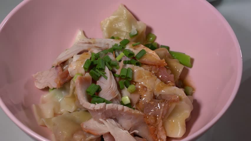 Two bowls of shrimp wonton and roasted red pork noodles and a bowl of soup.